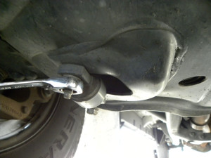 Loosen shock mount studs with a 13mm wrench. With all nuts loose, shock will drop out bottom hole.